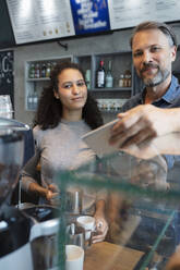 Selbstbewusster Café-Besitzer und Barista an der Theke eines Cafés - NURF00010