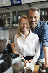 Happy coffee shop owner standing together at counter - NURF00015