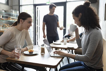 Colleagues sitting at table discussing in cafe - NURF00024