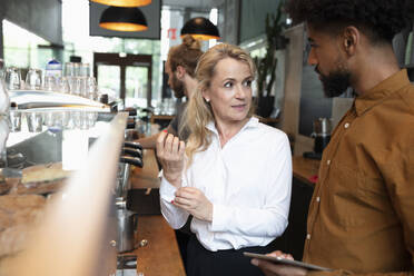 Café-Besitzer im Gespräch mit Barista im Coffeeshop - NURF00032