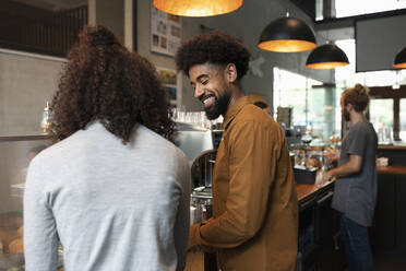 Smiling barista talking with colleague in cafe - NURF00033
