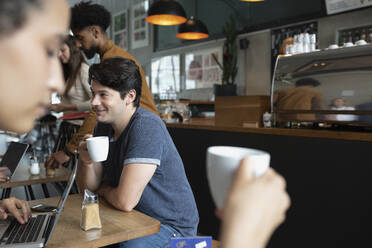 Lächelnder Mann trinkt Kaffee im Cafe - NURF00038