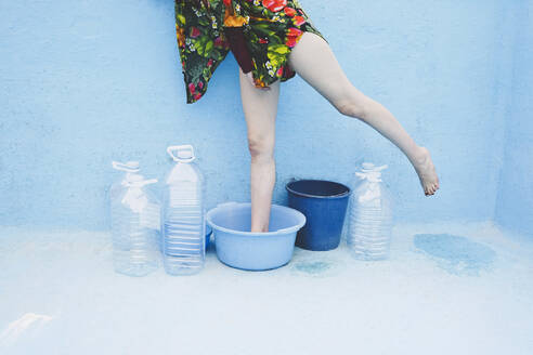 Woman standing in empty bucket inside swimming pool - SVCF00223