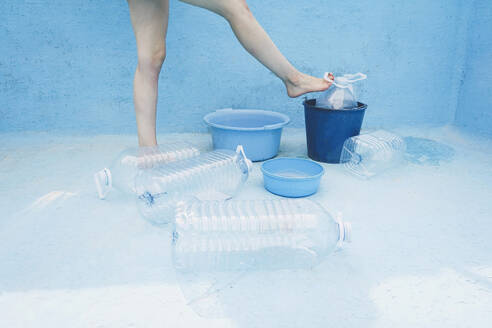 Woman standing by plastic bottle in empty pool - SVCF00224