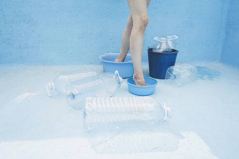 Woman standing inside empty buckets in swimming pool - SVCF00225