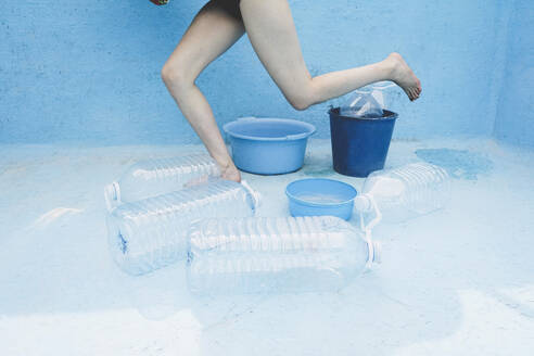 Woman amidst plastic bottles and buckets in empty pool - SVCF00226