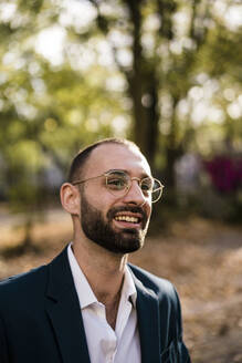 Happy businessman wearing eyeglasses in park - JOSEF15171