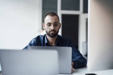 Businessman using laptop at desk in office - JOSEF15208