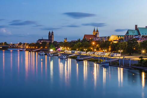 Deutschland, Sachsen-Anhalt, Magdeburg, Boote am Elbufer in der Abenddämmerung mit Stadtgebäuden im Hintergrund - WDF07169