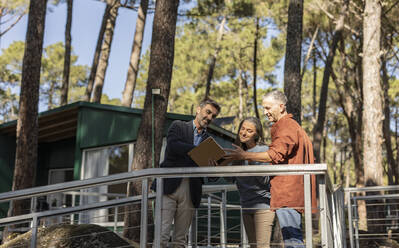 Immobilienmakler zeigt einem älteren Ehepaar ein energiesparendes Haus - JCCMF08283