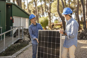 Fotovoltaik-Techniker tragen Solarmodul zusammen - JCCMF08332
