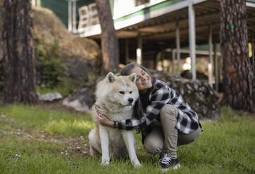 Mature woman embracing dog in garden - JCCMF08339