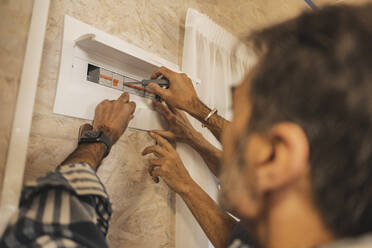 Technician installing fuse box at sustainble home - JCCMF08379