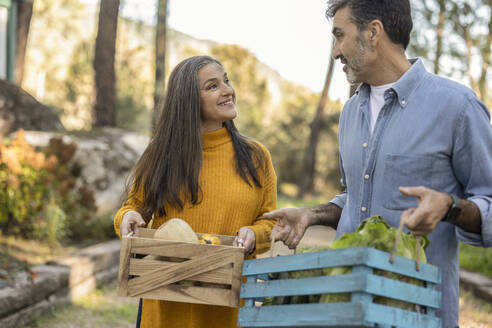 Mann und Frau tragen Kisten mit frisch geerntetem Bio-Gemüse - JCCMF08400