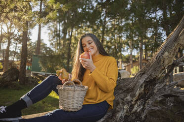 Smiling mature woman holding an apple in nature - JCCMF08470