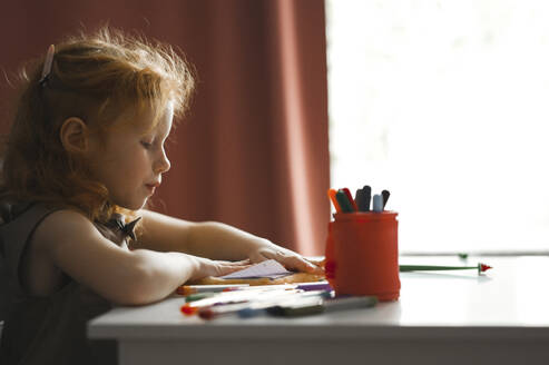 Girl drawing on paper sitting at desk in home - ANAF00600