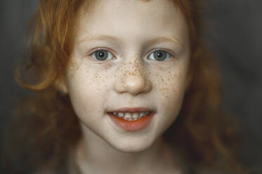 Little cute girl with freckles smiling, looking to camera, outdoors. Stock  Photo