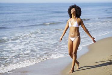 Sorglose Frau, die an einem sonnigen Tag am Strand spazieren geht - JSMF02559