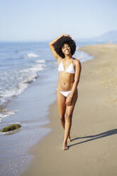 Smiling woman walking on beach - JSMF02560