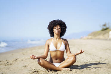 Junge Frau macht Yoga am Strand an einem sonnigen Tag - JSMF02565