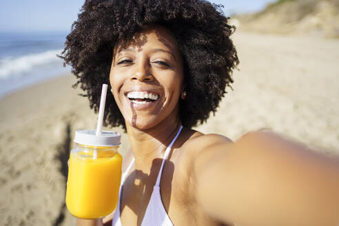 Glückliche Frau nimmt Selfie mit Orangensaft am Strand im Sommer - JSMF02570