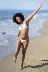 Fröhliche junge Frau, die sich am Strand amüsiert und Spaß hat - JSMF02577