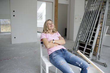 Smiling woman with eyes closed sitting in apartment - HMEF01496