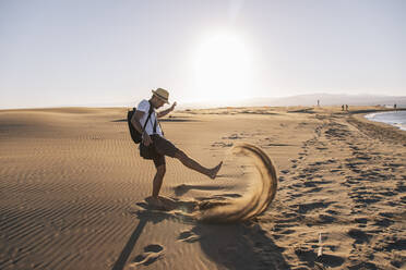 Man playing with sand at beach on sunset - MMPF00536