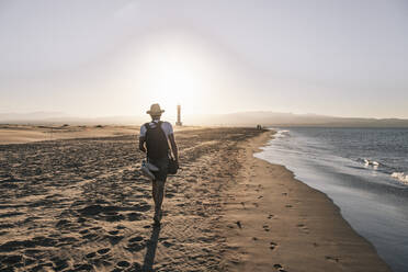 Mann geht in der Nähe des Ufers am Strand bei Sonnenuntergang - MMPF00539