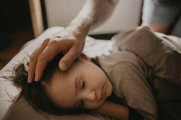 Father caressing son sleeping on bed at home - ANAF00622