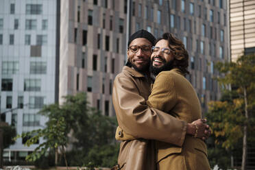 Homosexuelles Paar umarmt sich vor dem Gebäude außen - AGOF00310