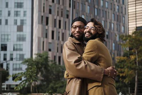 Gay couple embracing each other in front of building exterior - AGOF00310