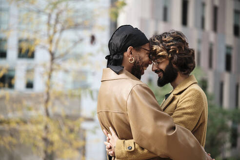Happy gay couple embracing in front of building - AGOF00313