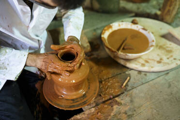 Craftsman molding pot on pottery wheel in factory - JSMF02608