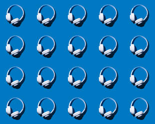 Muster aus Reihen von Kopfhörern flach auf blauem Hintergrund - GIOF15705