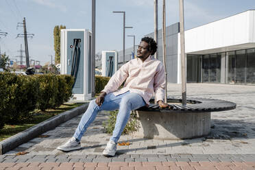 Young man sitting on bench at sunny day - OSF01153