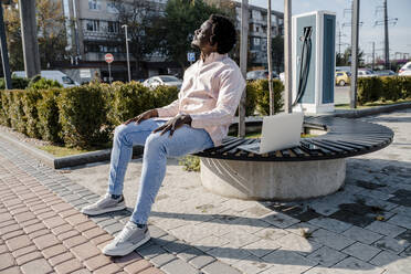 Young freelancer sitting on bench at sunny day - OSF01159