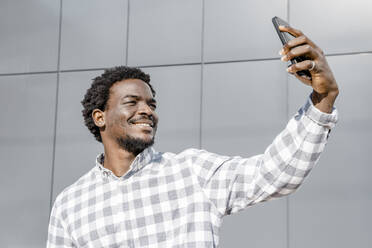 Mann macht Selfie mit Smartphone vor einer Wand - OSF01173