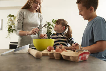 Mädchen mit Schwester und Bruder bei der Zubereitung von Keksen zu Hause - PMF02363