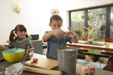 Boy helping sisters in preparing cookies at home - PMF02365