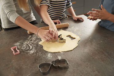 Kinderhände beim Ausstechen von Keksen am Küchentisch - PMF02378