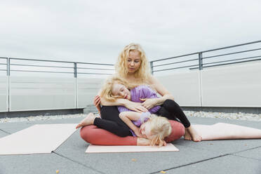 Mother embracing daughters on rooftop under sky - AANF00385