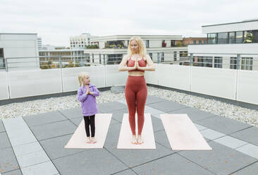 Nettes Mädchen übt Yoga mit Mutter auf dem Dach - AANF00393