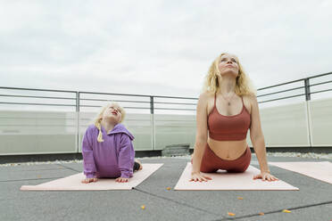 Mutter und Tochter üben gemeinsam Yoga auf der Terrasse - AANF00394