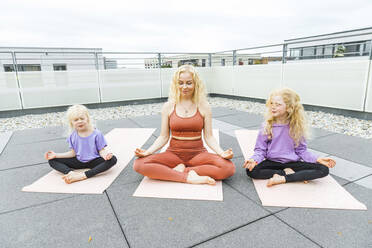 Mutter meditiert mit Töchtern auf dem Dach - AANF00397
