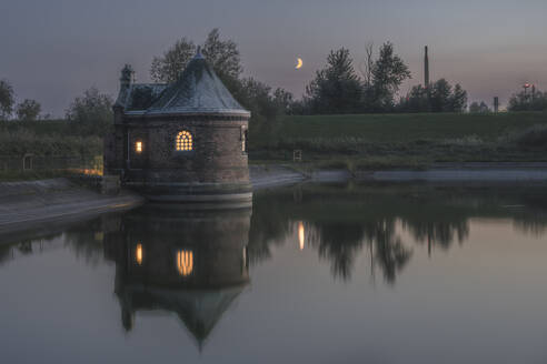 Deutschland, Hamburg, Historisches Filterhaus auf der Insel Kaltehofe spiegelt sich in der Elbe in der Abenddämmerung - KEBF02535