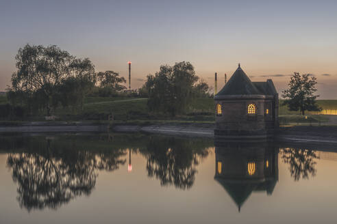 Deutschland, Hamburg, Historisches Filterhaus auf der Insel Kaltehofe spiegelt sich in der Elbe in der Abenddämmerung - KEBF02536