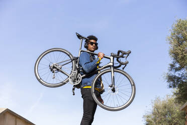 Junger Mann mit Fahrrad unter strahlend blauem Himmel - JPTF01127