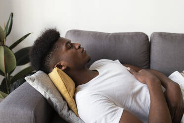 Young man sleeping on sofa at home - JPTF01138