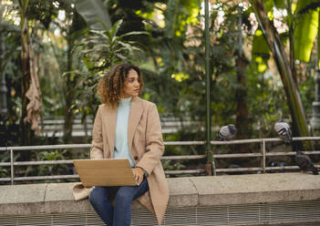 Businesswoman with laptop on bench - JCCMF08526